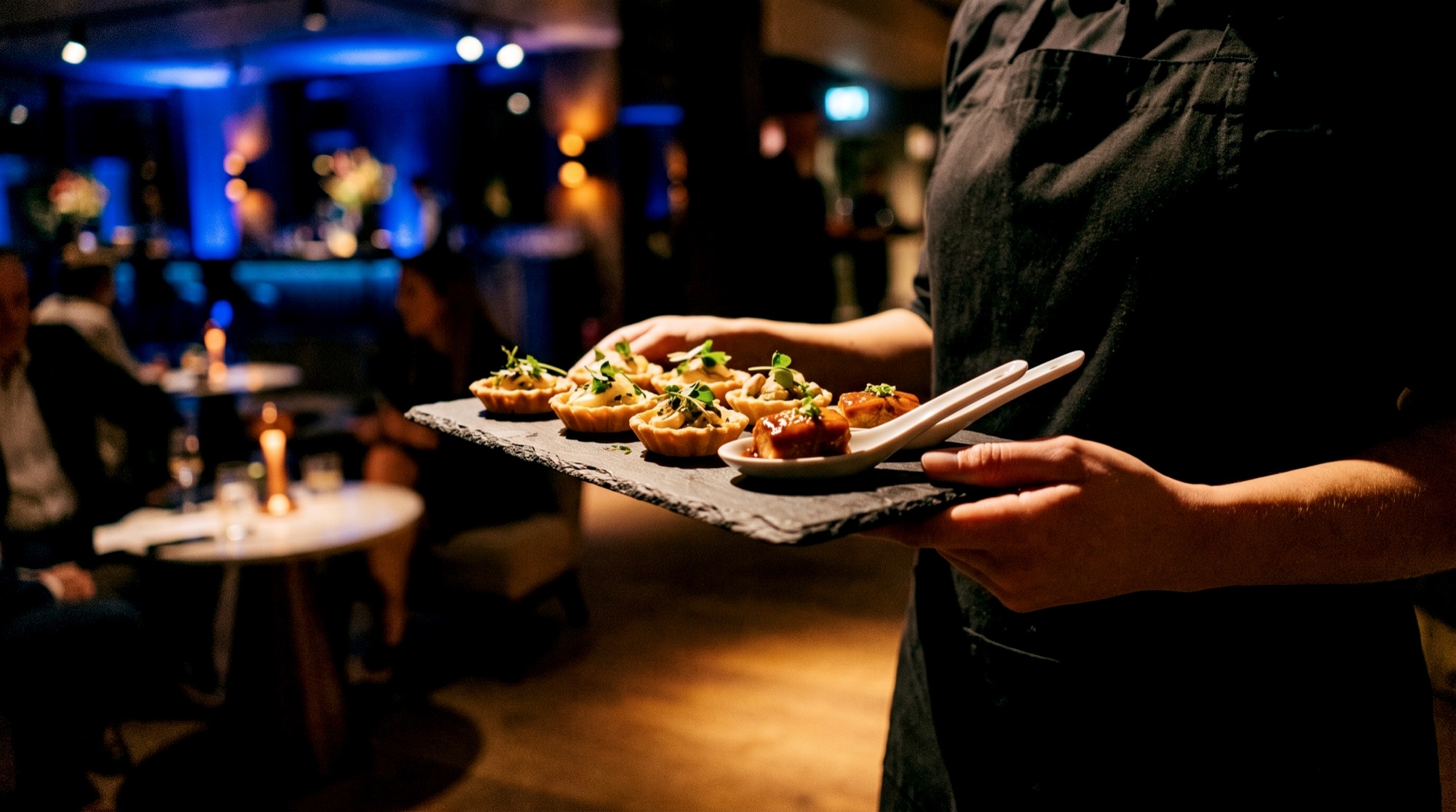 Service trägt Schieferplatte mit Fine-Dining-Fingerfood durch den Gala-Empfang