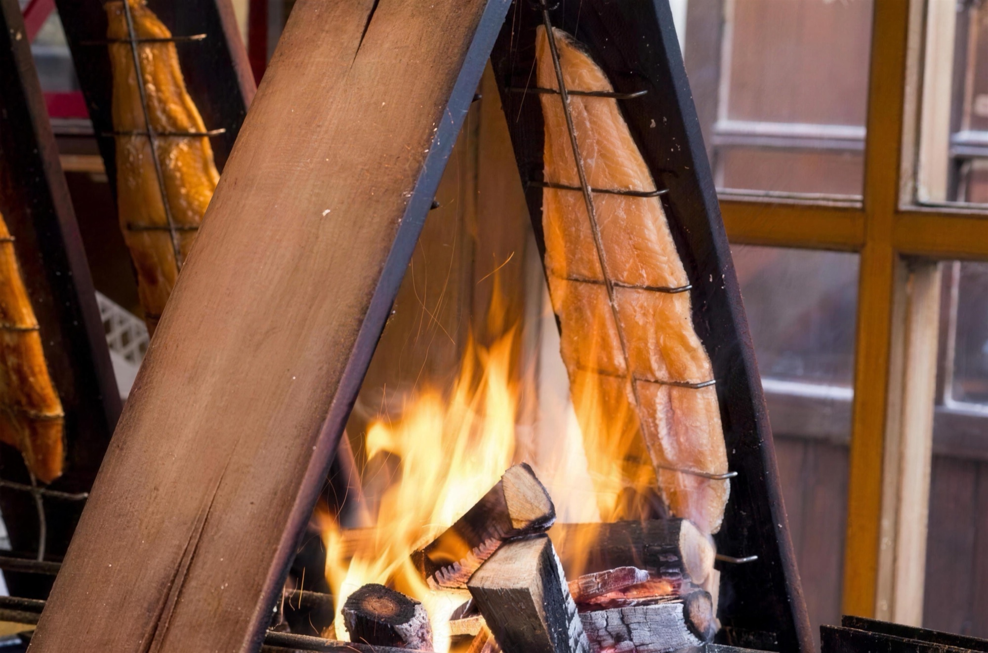 Fisch im BBQ-Smoker über offenem Feuer beim Firmenweihnachtsmarkt