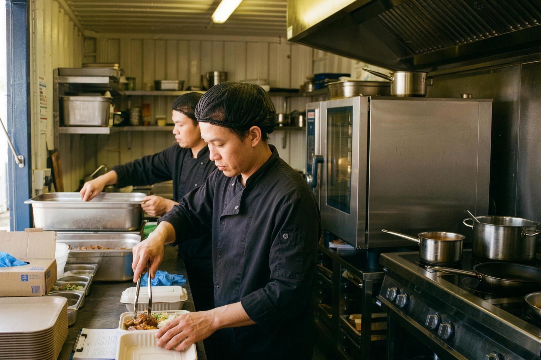 Betriebsverpflegung von STREET-KITCHEN: Team portioniert Mahlzeiten in der mobilen Küche