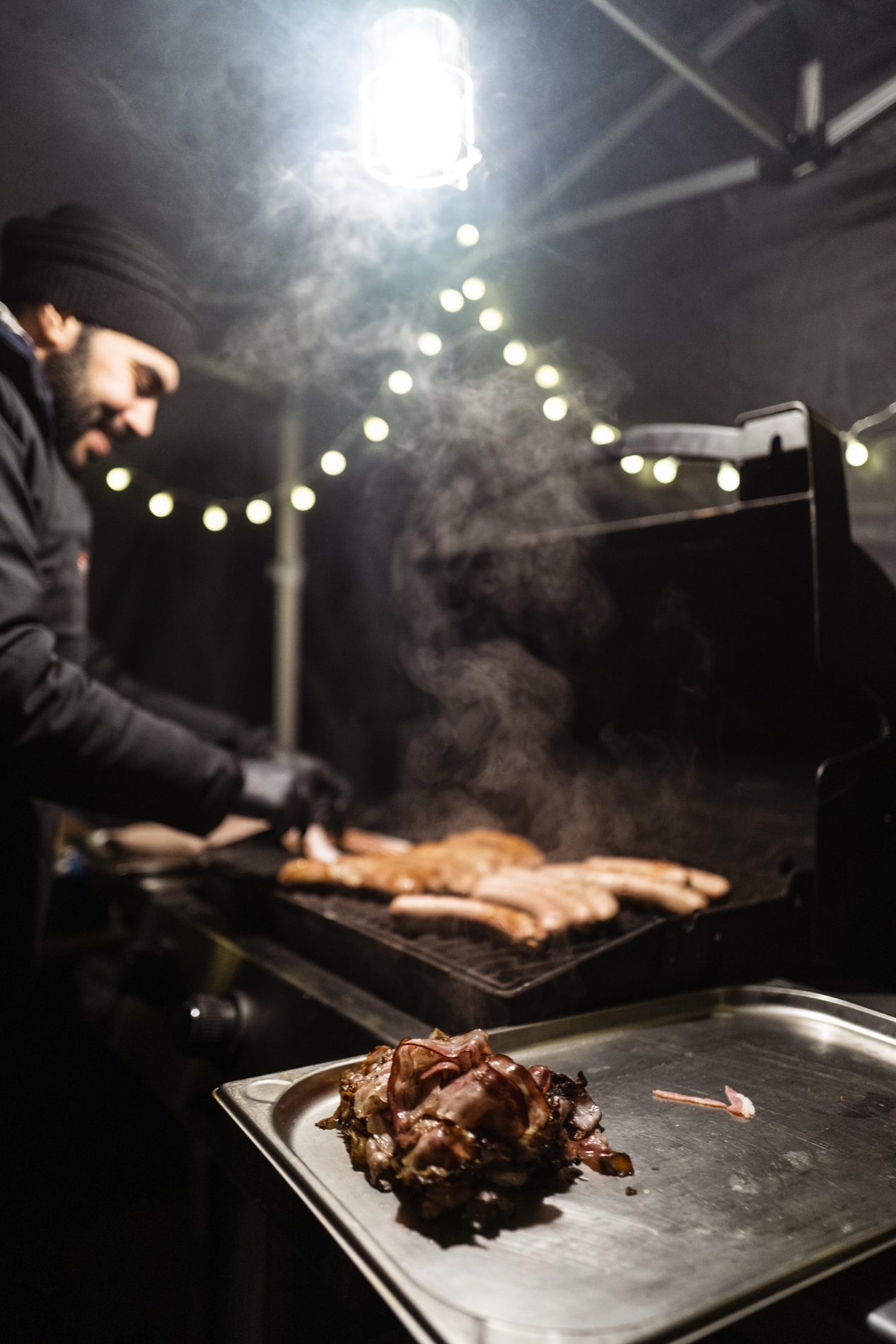 Koch am Grill mit Lichterkette auf dem Firmenweihnachtsmarkt